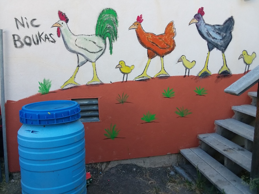 Painting on a building containing chickens trodding in the desert.